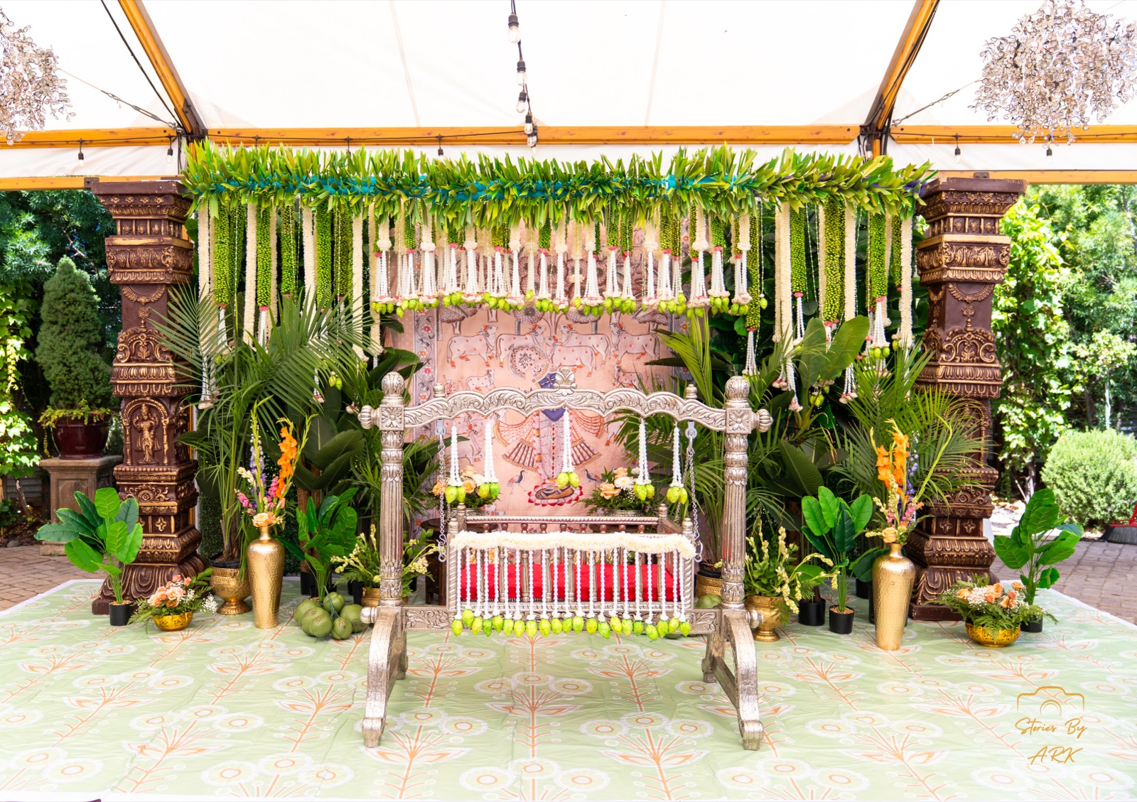 Silver oonjal swing with Pichwai backdrop and mango-leaf garlands by Me Events