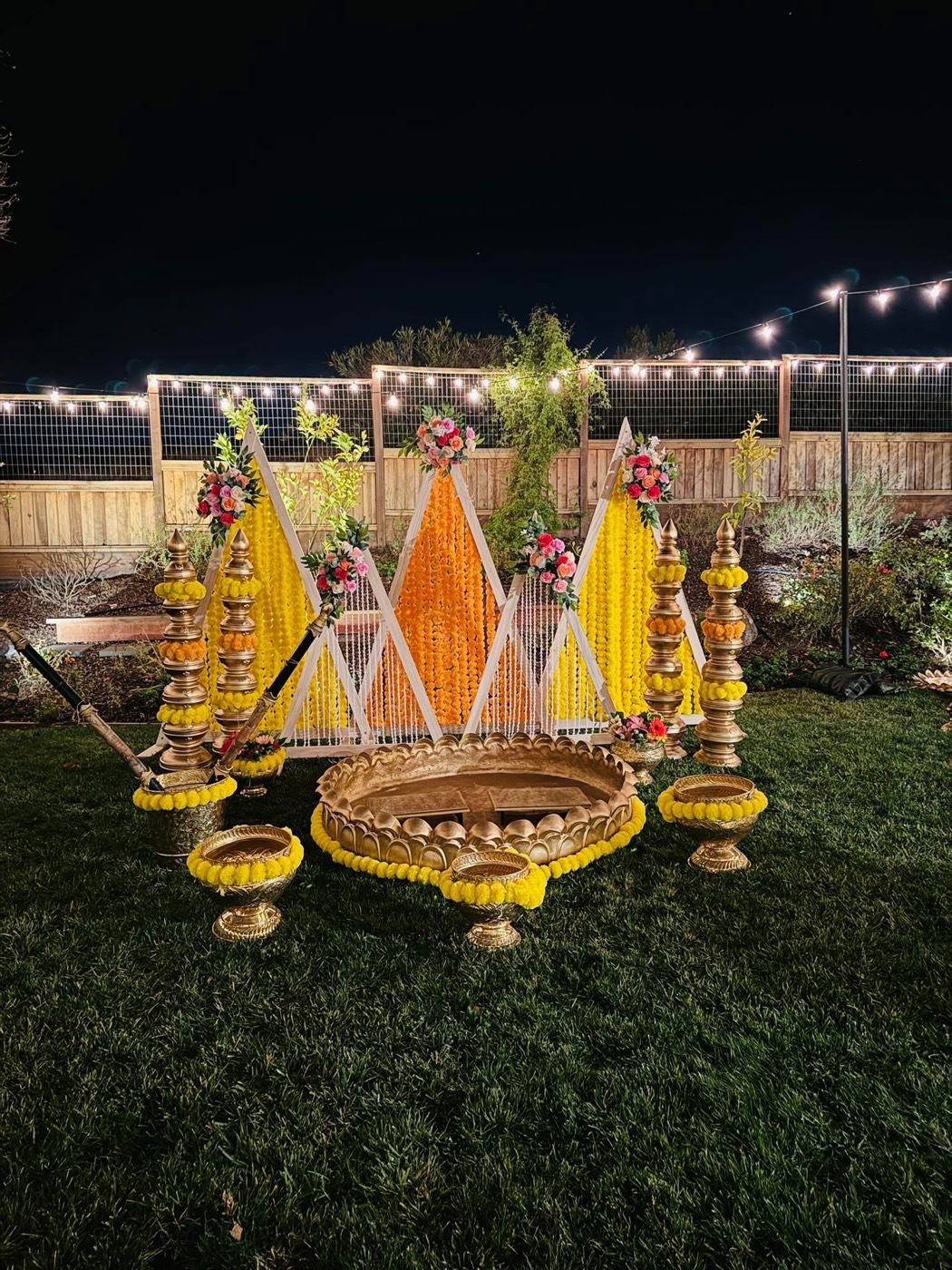 Outdoor haldi setup with marigold backdrop and string lights