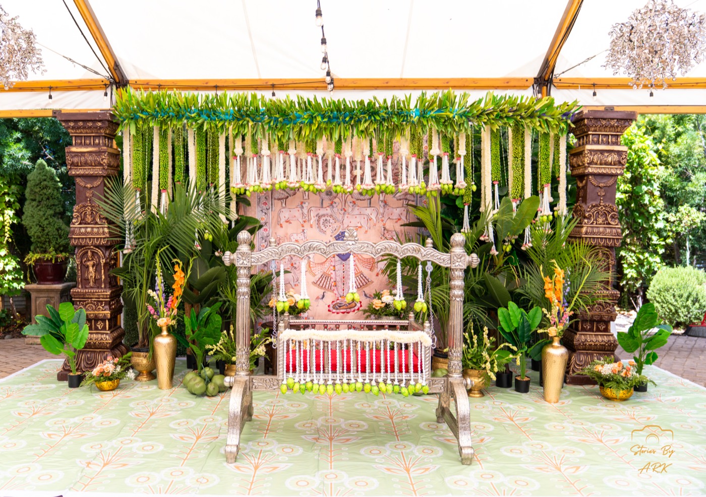 Silver oonjal swing with Pichwai backdrop and mango-leaf garlands